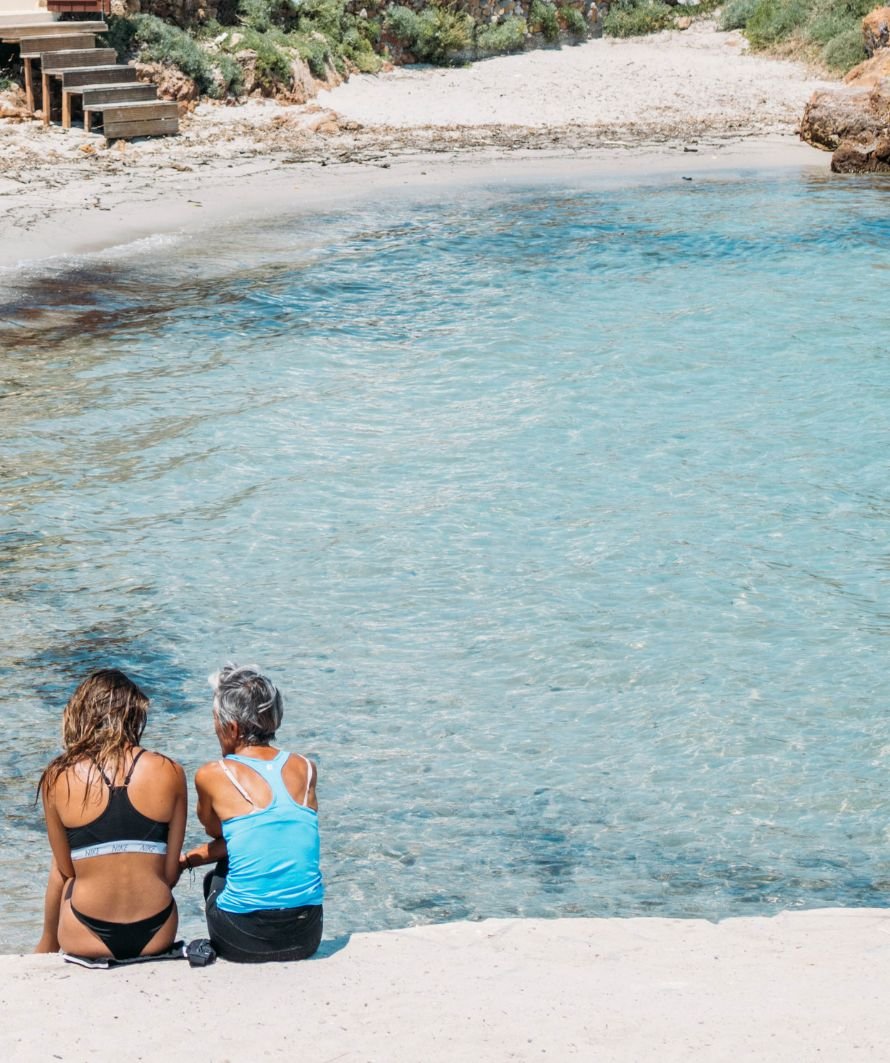 Deux femmes assises au bord d'une crique turquoise